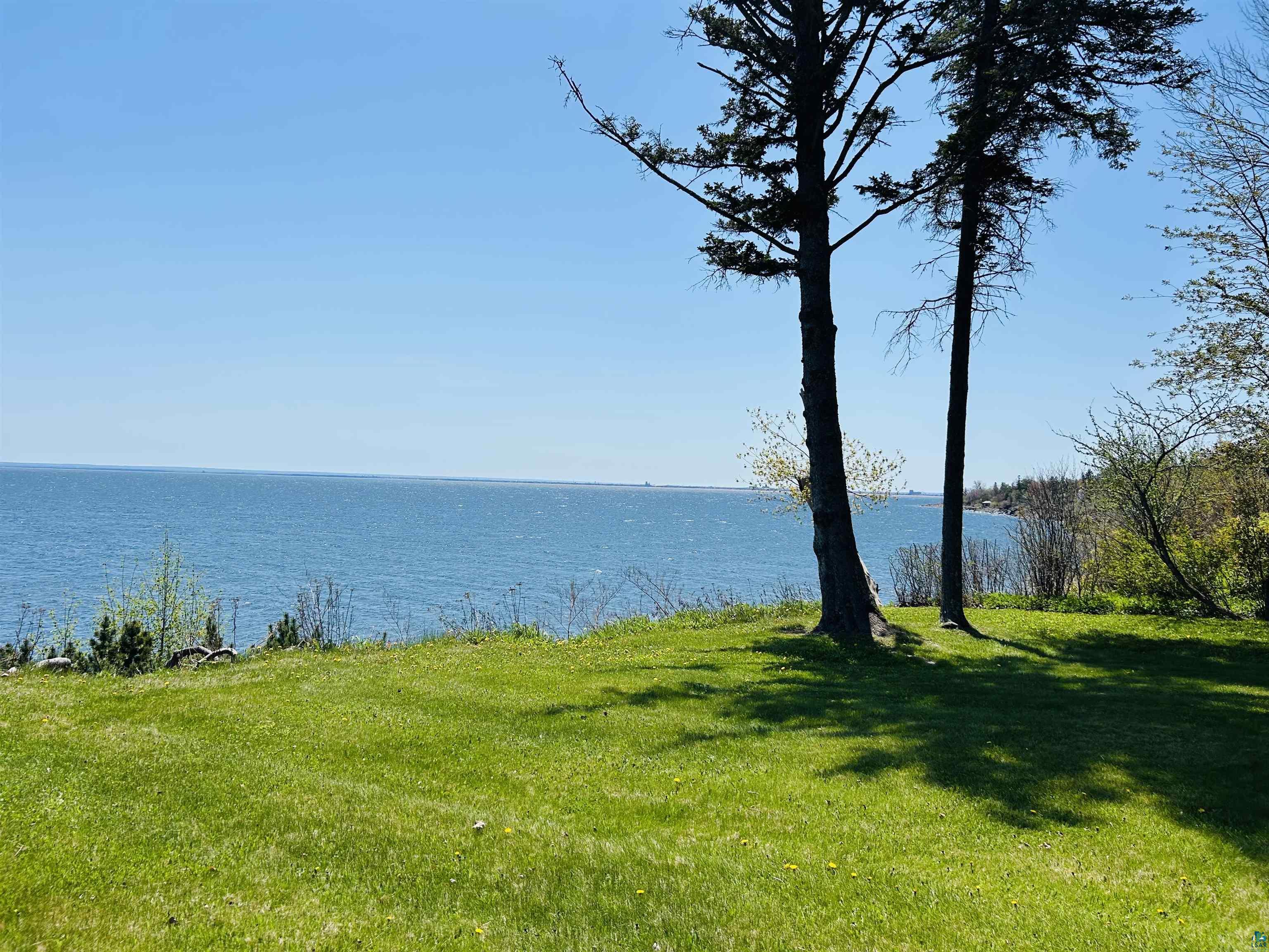 5090 London Road, Unit 1 Duluth, MN 55804 - Photo 45 of 54 Expansive waterfront property featuring a manicured lawn and mature evergreen trees