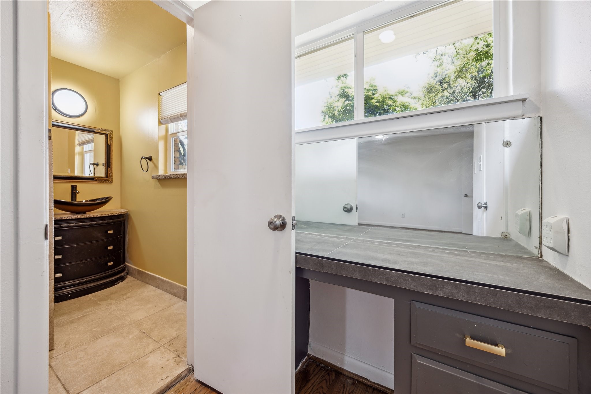 5419 Beechnut Street Houston, TX 77096 - Photo 20 of 28 Primary suite layout featuring a granite vanity with vessel sink and framed mirror, seamlessly connected to the dressing area with built-in storage and natural light.