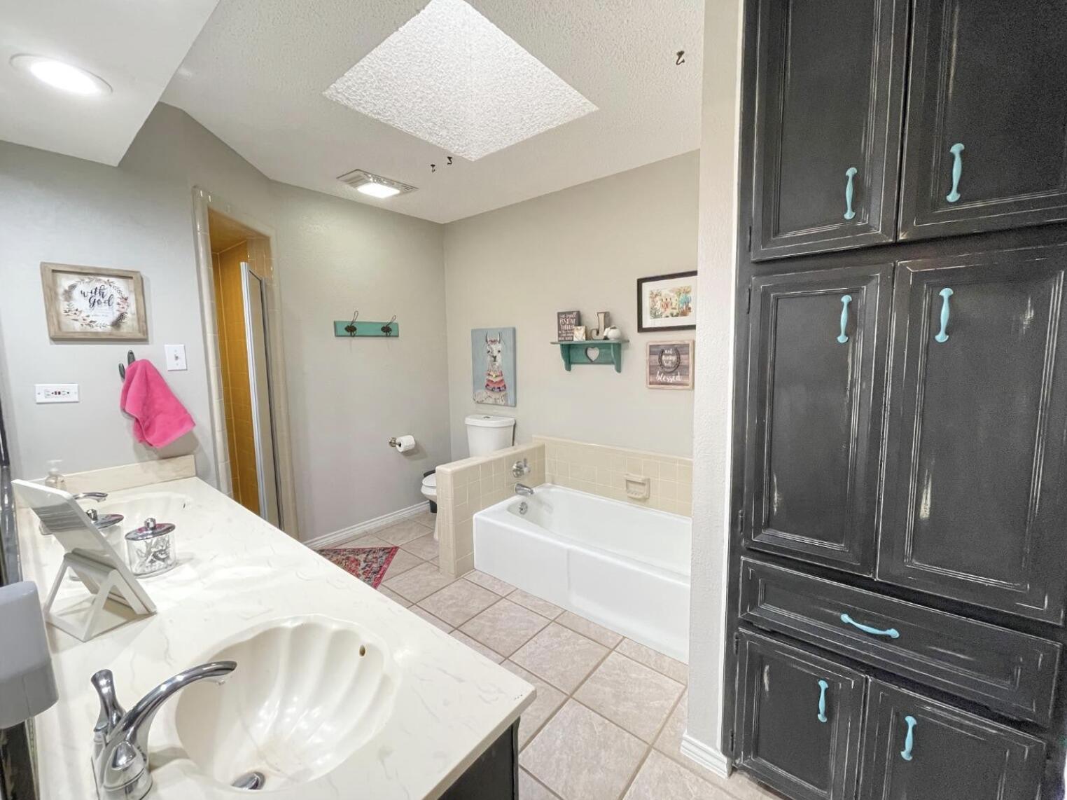 5413 83rd Street Lubbock, TX 79424 - Photo 11 of 21 a en suite bathroom with a tub sink and mirror
