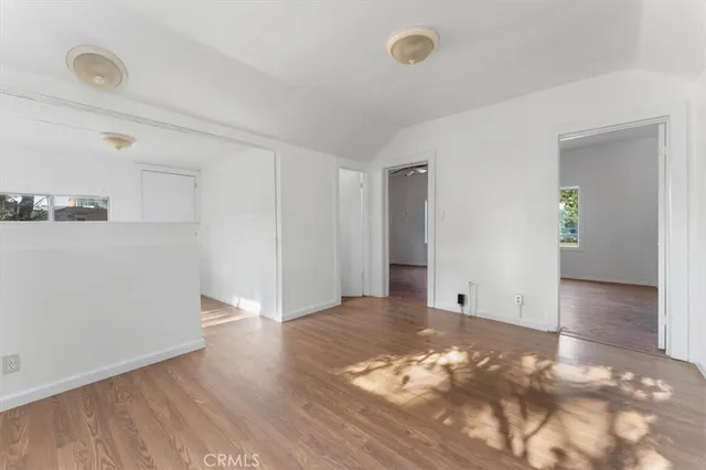 a view of an empty room with wooden floor and closet