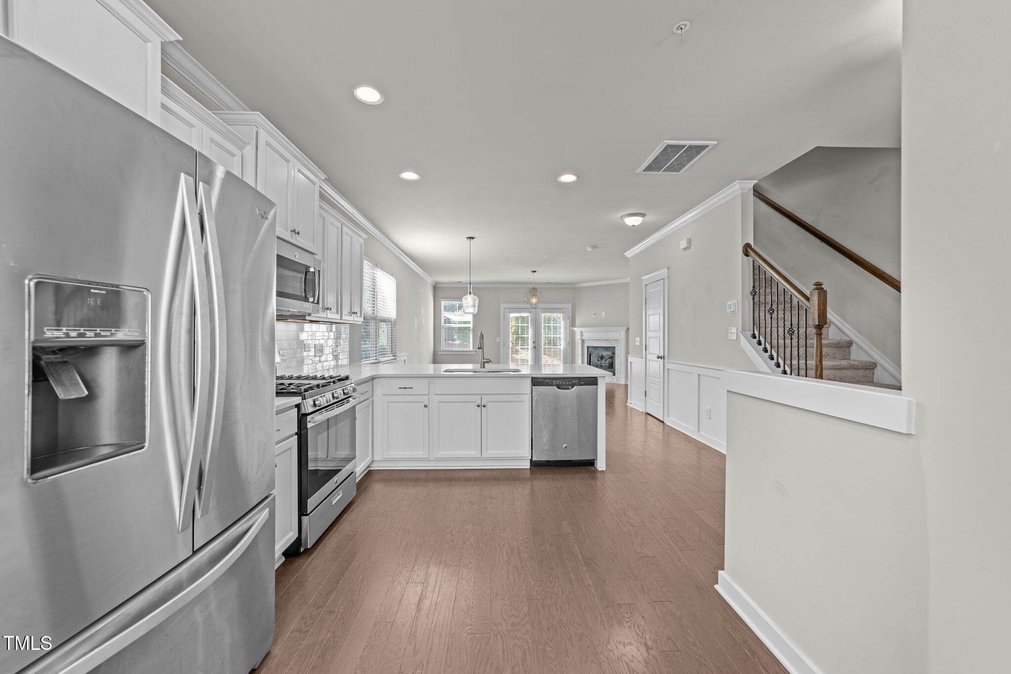7824 Allscott Way Raleigh, NC 27612 - Photo 6 of 26 a kitchen with white cabinets and stainless steel appliances