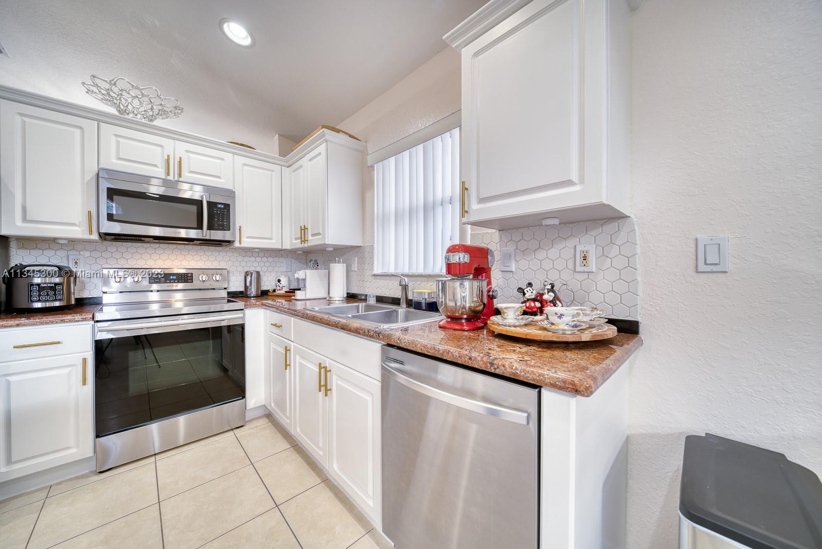 1635 Southeast 20th Place Homestead, FL 33035 - Photo 19 of 28 a kitchen with stainless steel appliances granite countertop a sink and stove top oven