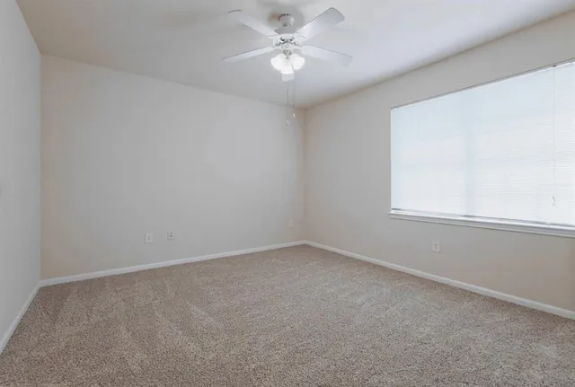 an empty room with a window and a fan
