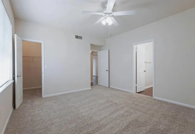 an empty room with a ceiling fan and a fan