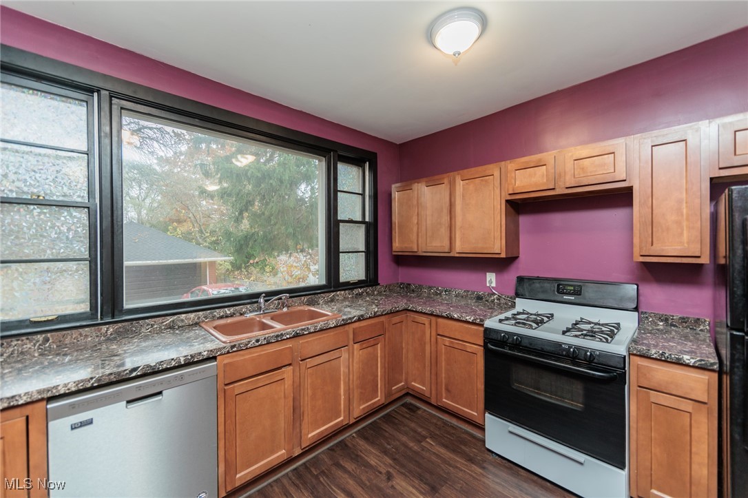 3181 Warren Road Cleveland, OH 44111 - Photo 7 of 28 Kitchen with sink, white range with gas cooktop, dark stone counters, stainless steel dishwasher, and dark hardwood / wood-style flooring