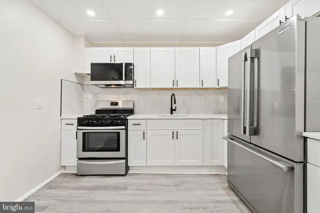 a kitchen with stainless steel appliances white cabinets and a refrigerator