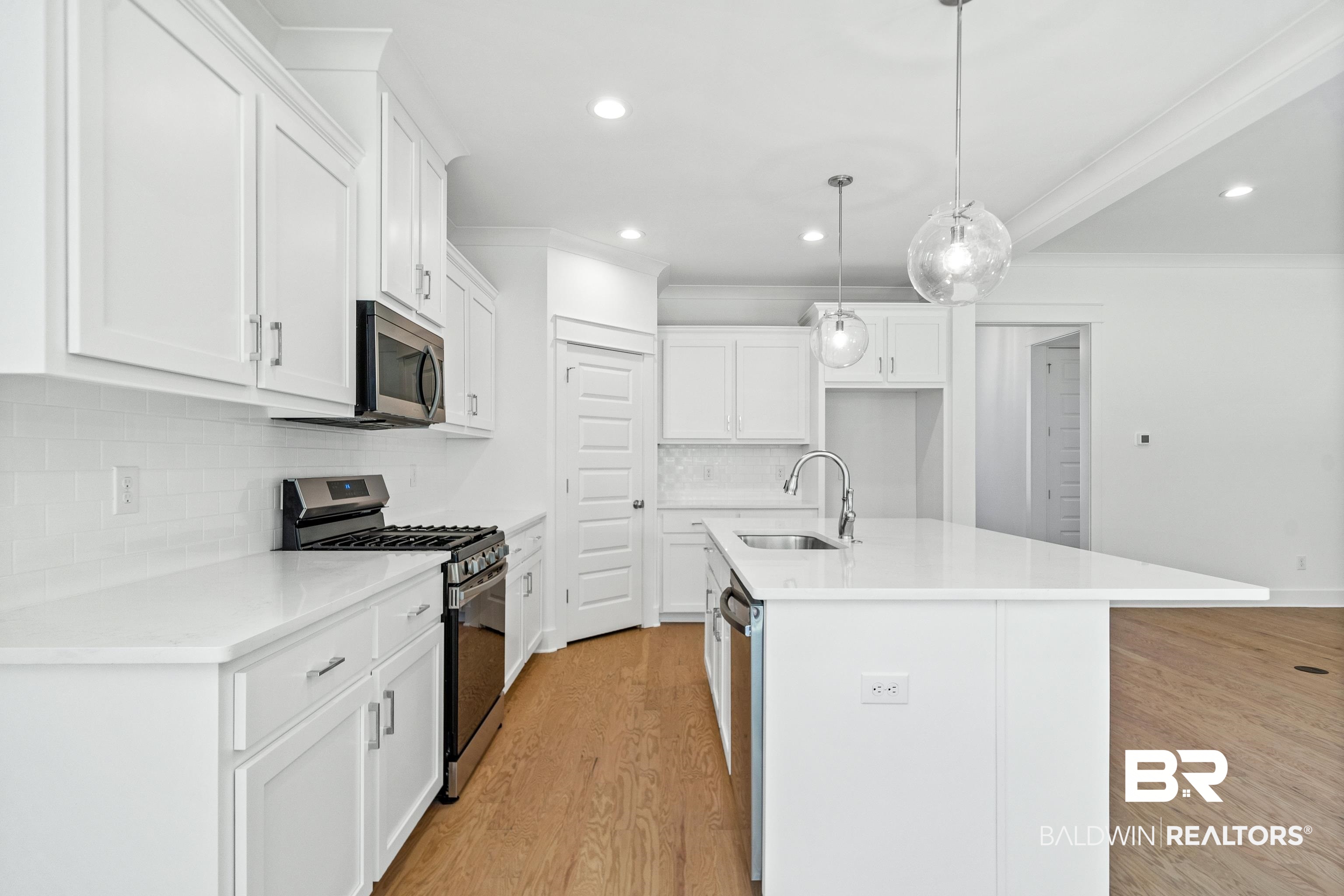 25927 Capra Court Daphne, AL 36526 - Photo 11 of 37 Kitchen featuring appliances with stainless steel finishes, a kitchen island with sink, sink, and white cabinetry