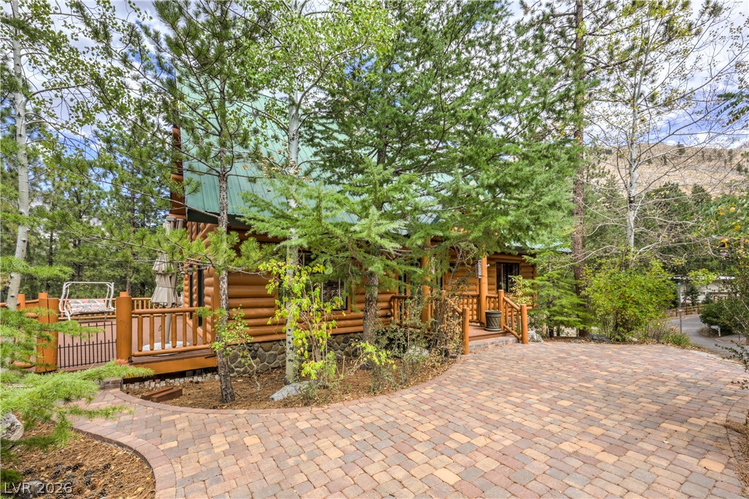 322 Ski Trail Road Mount Charleston, NV 89124 - Photo 3 of 58 Mature trees frame a charming log exterior fronted by a spacious paver driveway.