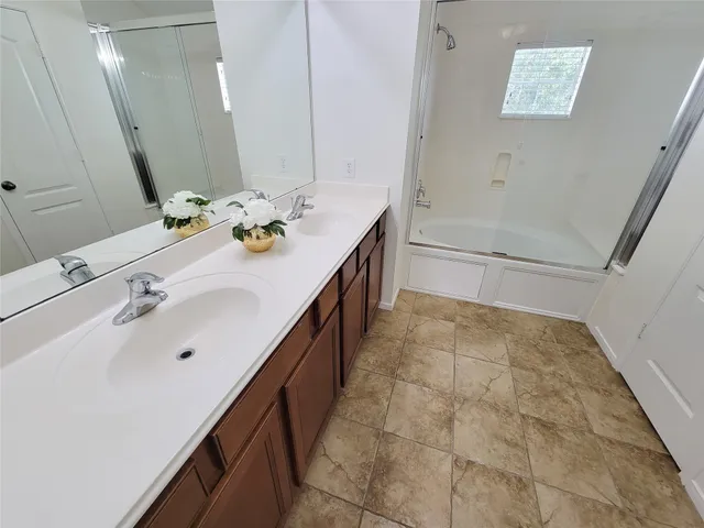 a bathroom with a double vanity sink a mirror and a bathtub