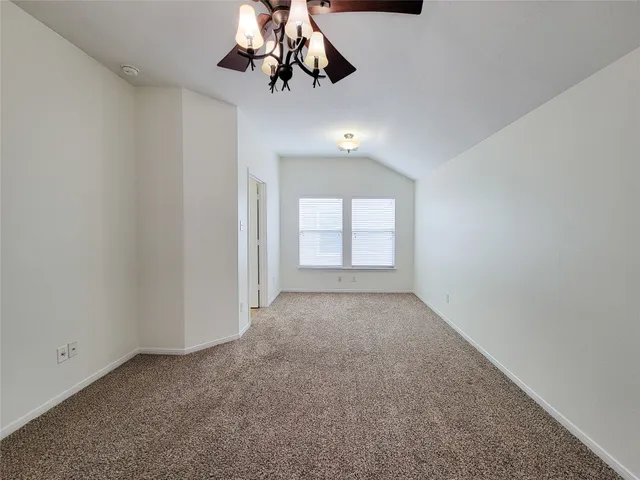 a view of an empty room and window with a chandelier fan