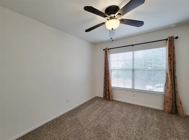 an empty room with a window and a fan