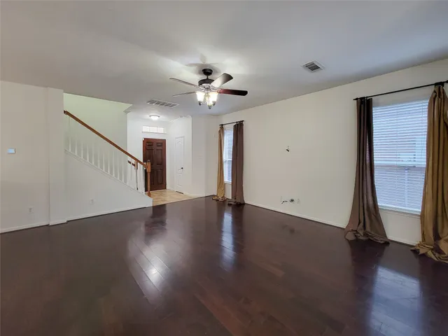 a view of an empty room with a window and wooden floor