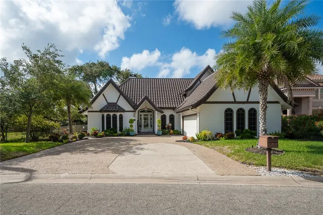 a front view of a house with a garden and trees