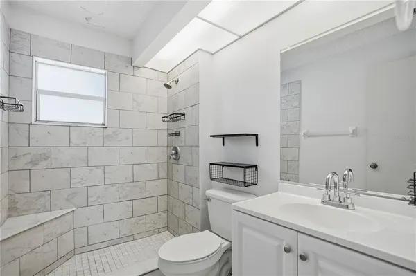 a bathroom with a granite countertop sink a toilet and shower