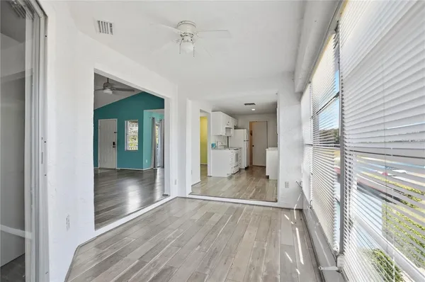 an empty room with wooden floor a ceiling fan and windows