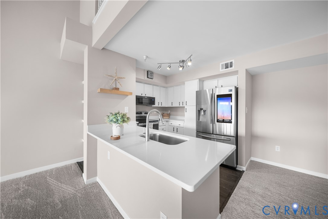 a kitchen with stainless steel appliances a sink a stove and white cabinets