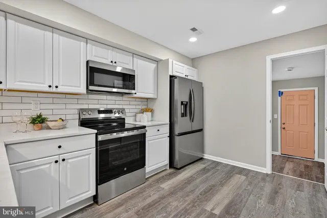 a kitchen with stainless steel appliances granite countertop a refrigerator stove and white cabinets