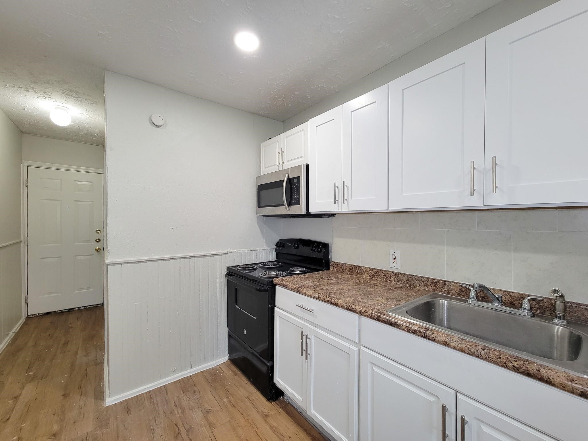 711 Ave A, Unit 4 La Marque, TX 77568 - Photo 11 of 21 a kitchen with granite countertop white cabinets and a stainless steel appliances