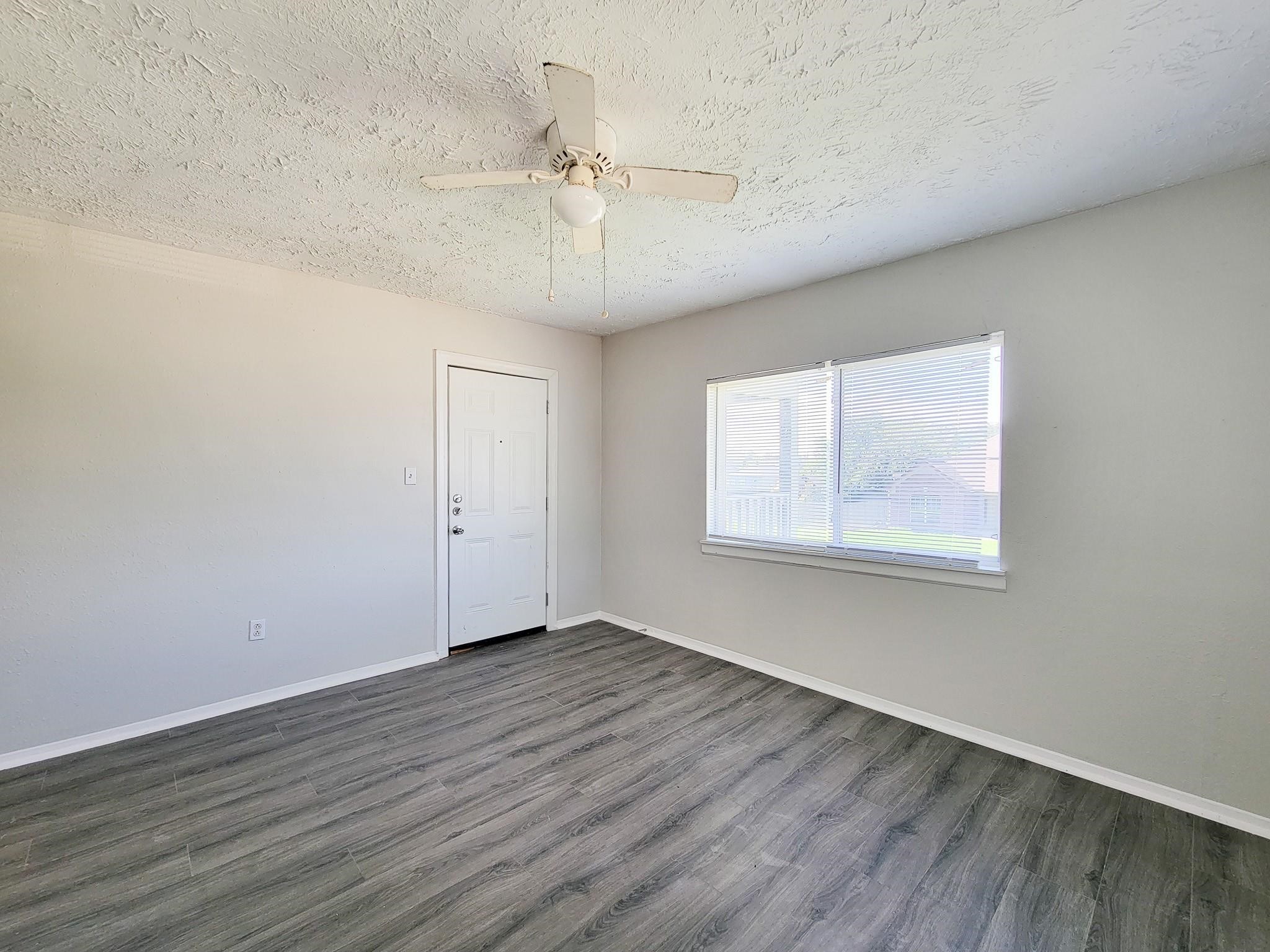 711 Ave A, Unit 4 La Marque, TX 77568 - Photo 7 of 21 an empty room with wooden floor chandelier fan and windows