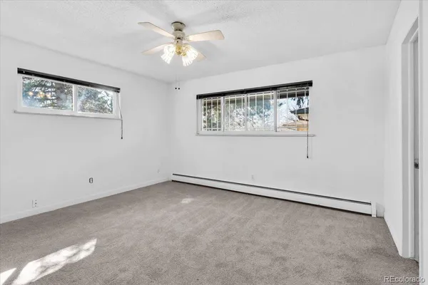 an empty room with a chandelier fan and windows