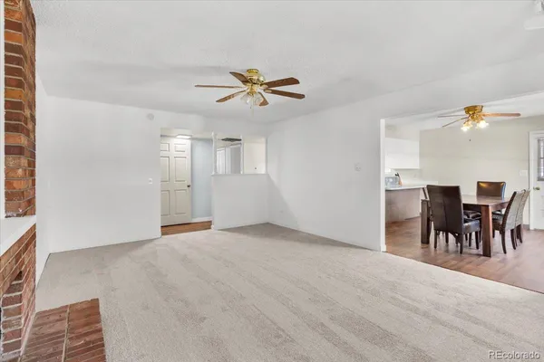 an empty room with chandelier fan and windows
