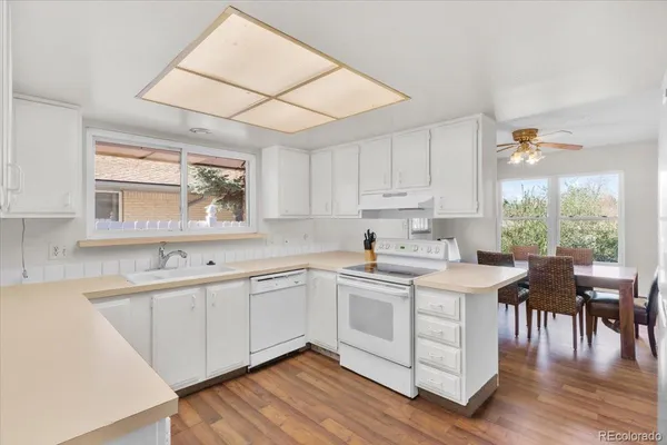 a kitchen with white cabinets sink dining table and chairs