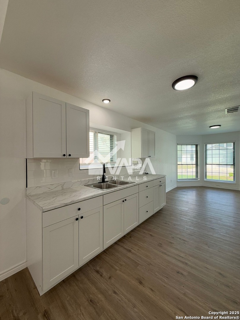 6406 Gray Ridge San Antonio, TX 78233 - Photo 5 of 15 a large white kitchen with wide window and wooden floor