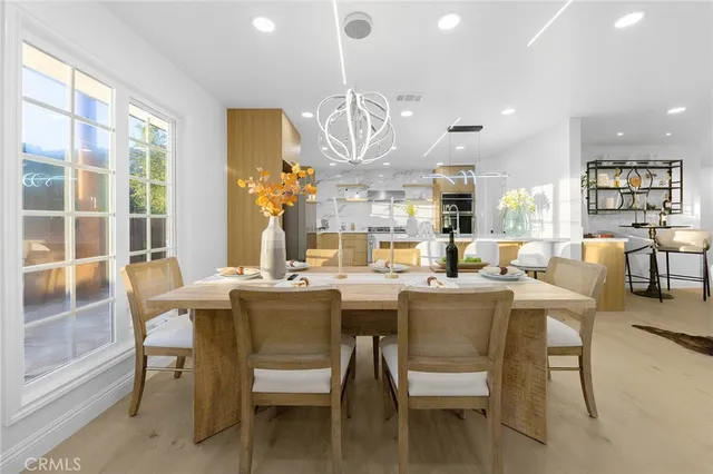 a dining room with wooden floor a chandelier a wooden table and chairs