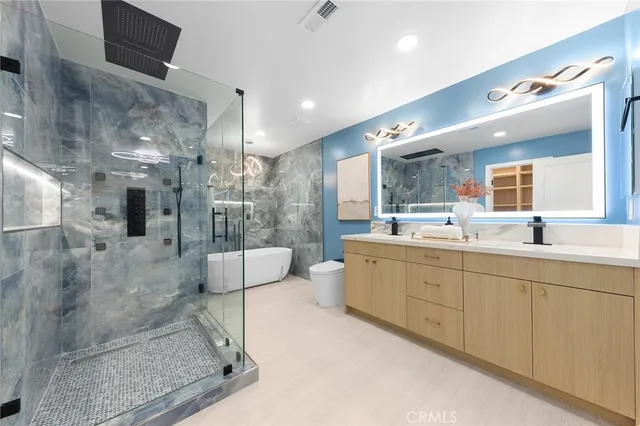 a bathroom with a double vanity sink a toilet a mirror and shower