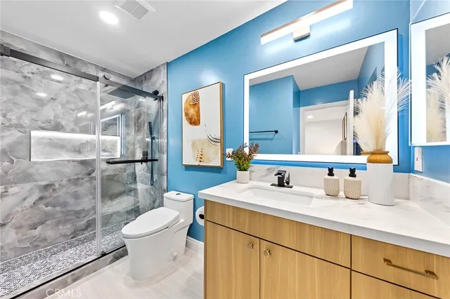 a bathroom with a granite countertop sink mirror vanity and toilet