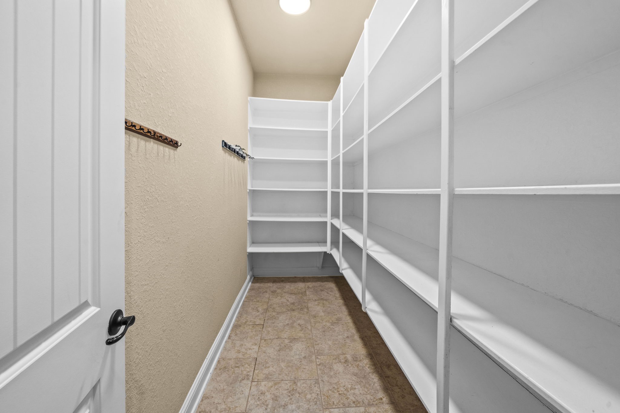 14215 Spindle Arbor Road Cypress, TX 77429 - Photo 19 of 47 This spacious pantry features ample white shelving for organized storage, a tiled floor, and a simple, lighted design.
