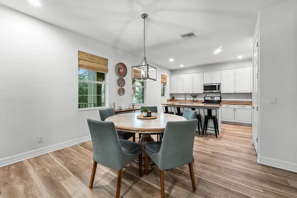 a view of a dining room and livingroom with furniture wooden floor a rug a painting and a chandelier