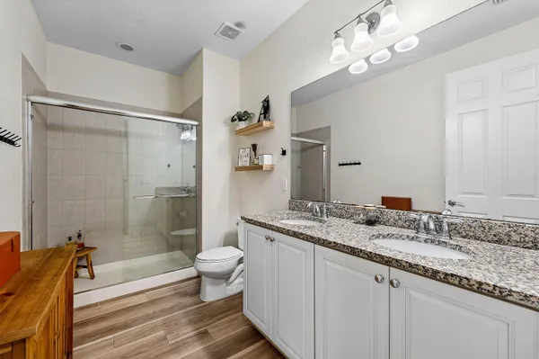 a bathroom with a granite countertop sink a toilet a mirror and shower