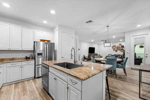 a kitchen with stainless steel appliances granite countertop a sink refrigerator and cabinets