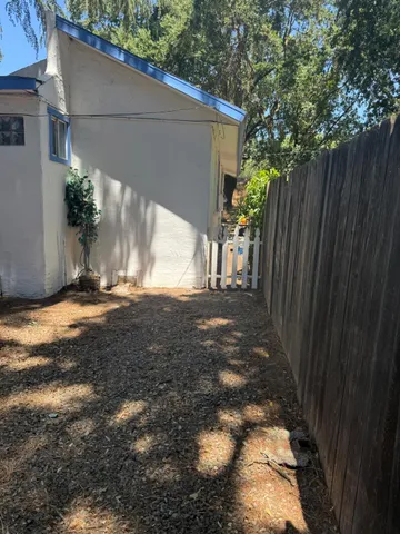 a view of a backyard with a large tree and wooden fence