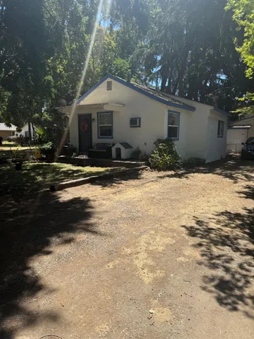 a view of a backyard with table and chairs potted plants and large tree