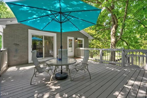 a patio with wooden floor a yard a table and chairs