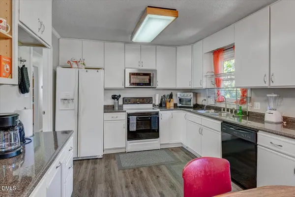a kitchen with granite countertop a refrigerator stove top oven and sink