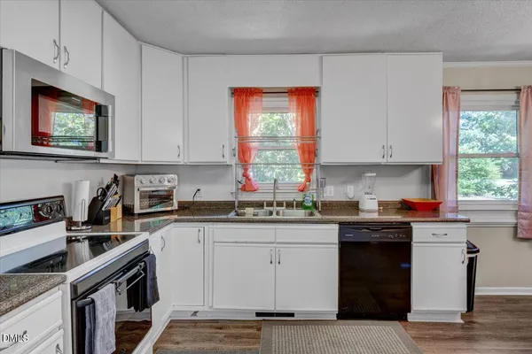 a kitchen with stainless steel appliances granite countertop a stove a sink dishwasher and cabinets with wooden floor