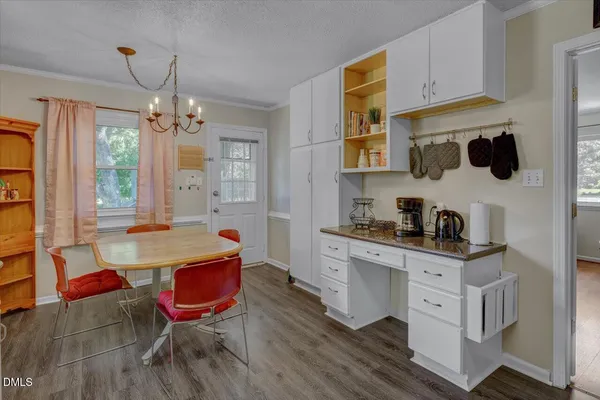 a kitchen with stainless steel appliances granite countertop a sink a stove a dining table and chairs with wooden floor