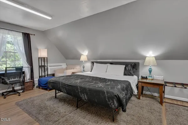 a bedroom with a bed a table and large windows