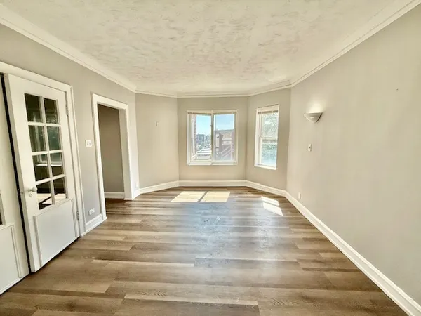 a view of an empty room with window and wooden floor