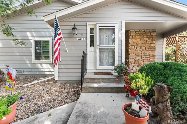a front view of small house with outdoor seating and flowers