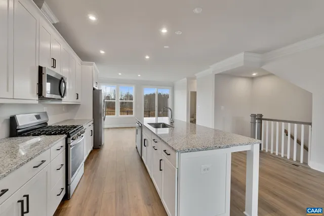 a kitchen with granite countertop a stove top oven a sink a counter space and cabinets