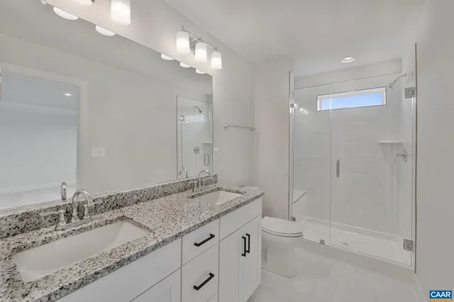 a bathroom with a granite countertop sink a toilet and shower
