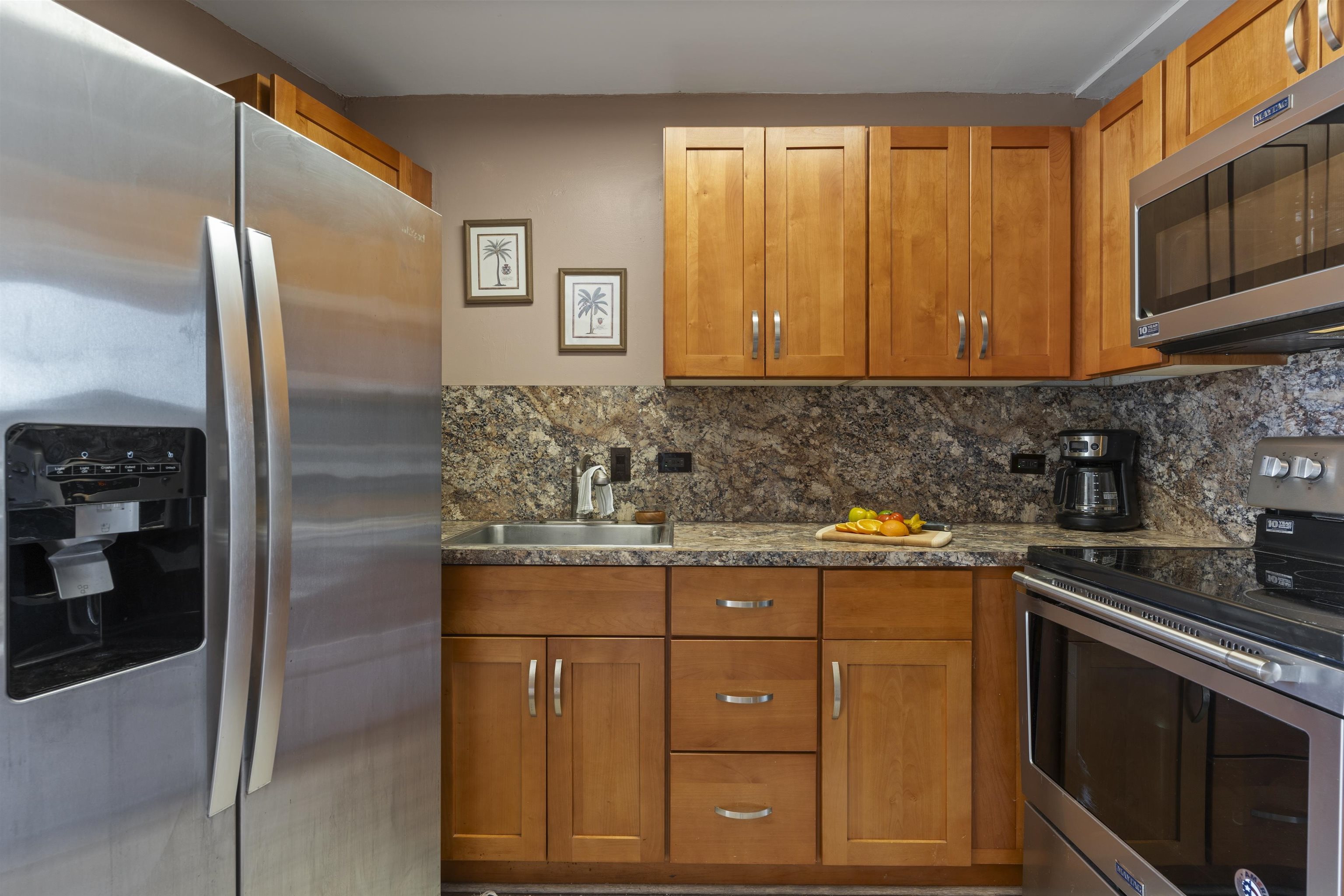 3823 Lower Honoapiilani Road, Unit 401 Lahaina, HI 96761 - Photo 18 of 40 a kitchen with stainless steel appliances granite countertop a stove a refrigerator and a sink