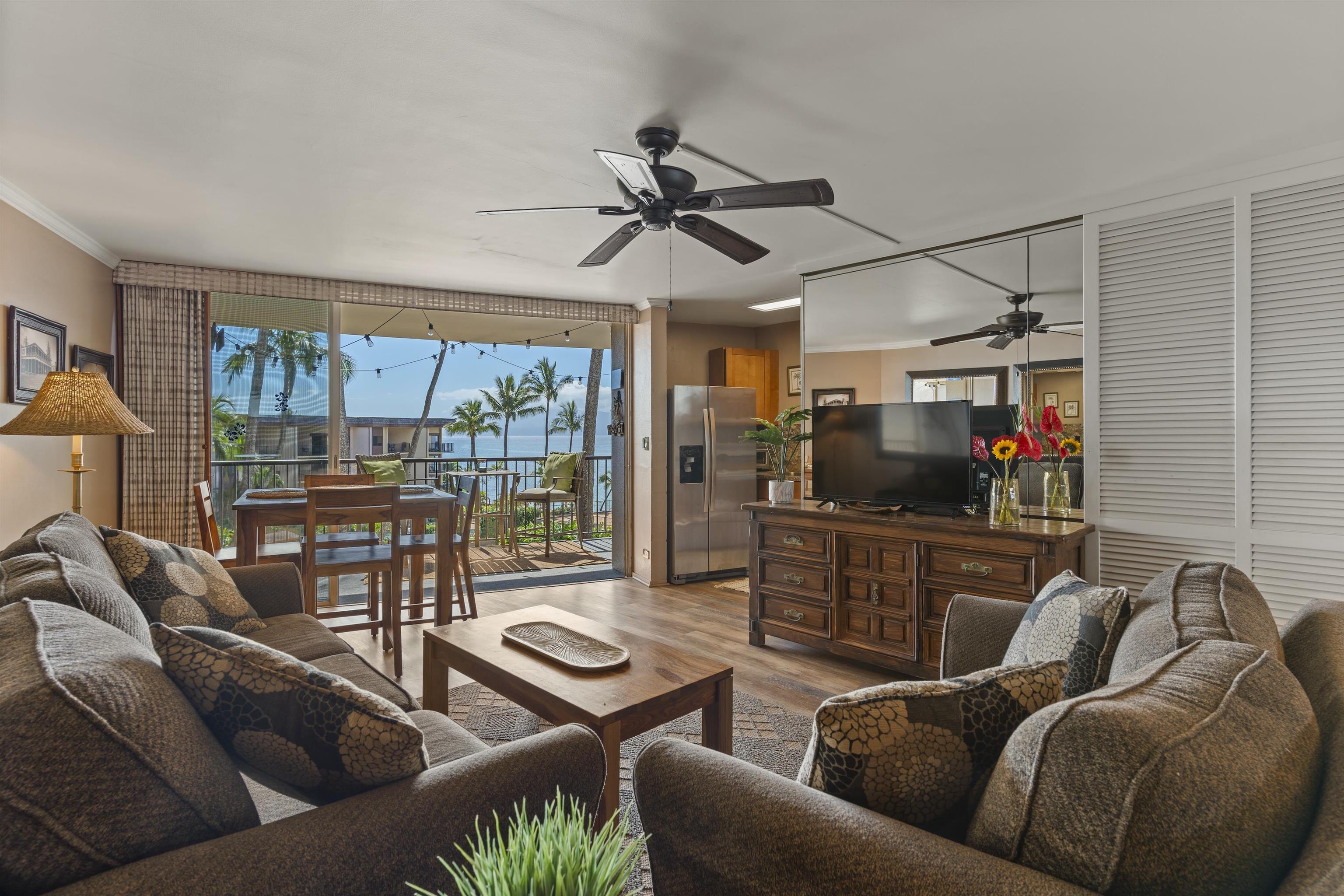 3823 Lower Honoapiilani Road, Unit 401 Lahaina, HI 96761 - Photo 3 of 40 a living room with furniture a ceiling fan and a flat screen tv