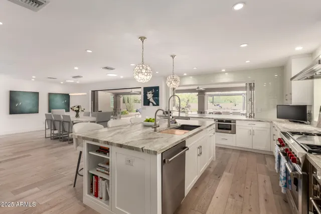 a kitchen with a stove a sink a counter top space and living room view