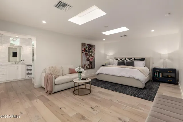 a spacious bedroom with a bed a couch and chandelier