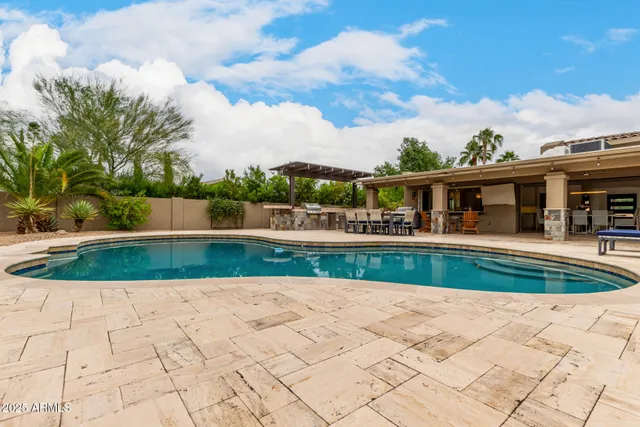 a view of swimming pool and a chairs in front of house